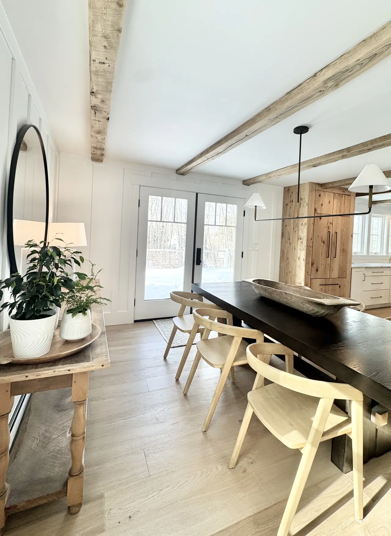 A dining room with an exposed beam and coastal light in the Arundel, Maine home