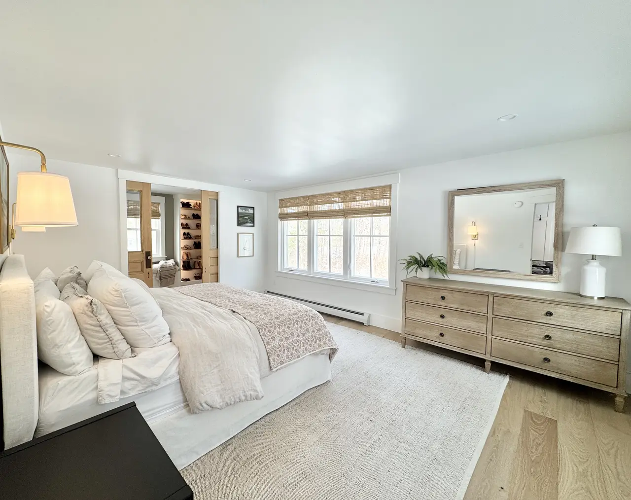 Primary bedroom in soft neutrals with a wood dresser