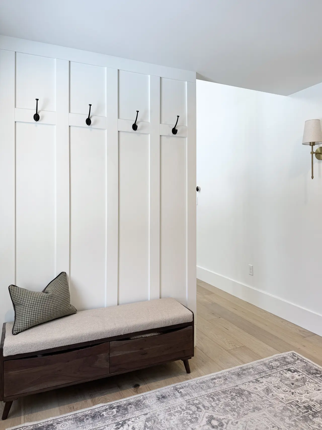 Board-and-batten entry with a bench, rug, and hooks